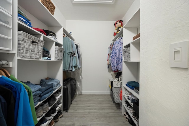 walk in closet with light wood-style floors