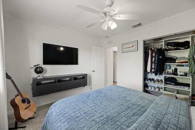 bedroom featuring wood finished floors, visible vents, ceiling fan, a closet, and crown molding