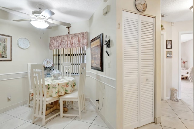 dining area featuring visible vents, baseboards, ceiling fan, light tile patterned floors, and a textured ceiling