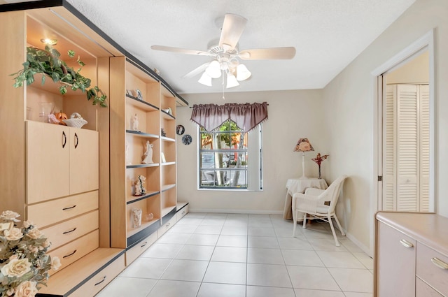 sitting room featuring light tile patterned floors, baseboards, and a ceiling fan