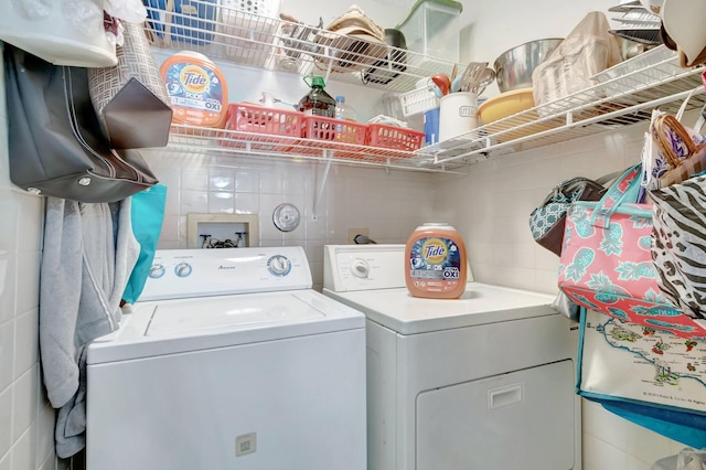 laundry room featuring washing machine and clothes dryer, laundry area, and tile walls