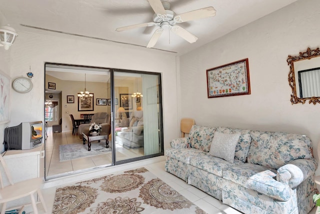 tiled living room with ceiling fan with notable chandelier