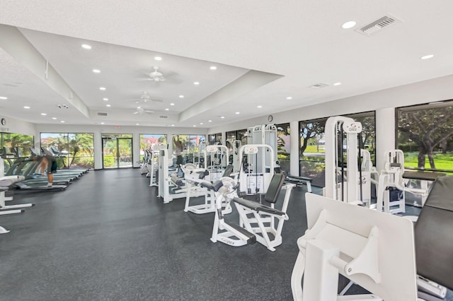 gym featuring visible vents, recessed lighting, a raised ceiling, and a ceiling fan