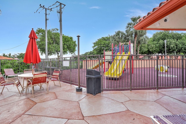 view of patio / terrace featuring playground community, outdoor dining space, and fence