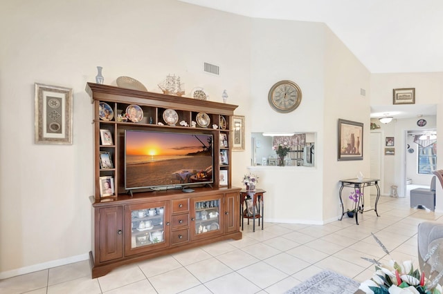 living room with light tile patterned floors, baseboards, visible vents, and high vaulted ceiling