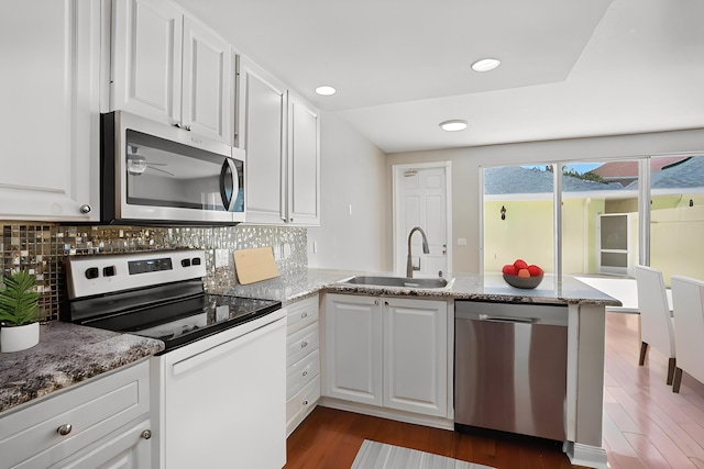 155 Waterford Dr, Jupiter, FL 33458 - kitchen featuring stainless steel appliances, a sink, a peninsula, dark wood-style floors, and white cabinetry