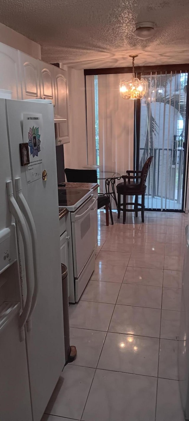 3450 Blue Lake Dr Unit 204, Pompano Beach, FL 33064 - kitchen featuring a notable chandelier, white appliances, a textured ceiling, light tile patterned flooring, and white cabinets