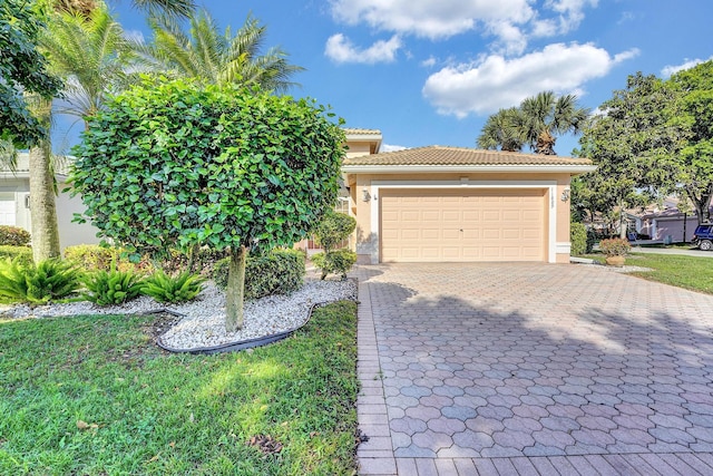 view of front of house featuring a tile roof, decorative driveway, an attached garage, and stucco siding