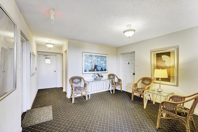 hallway featuring dark carpet and a textured ceiling