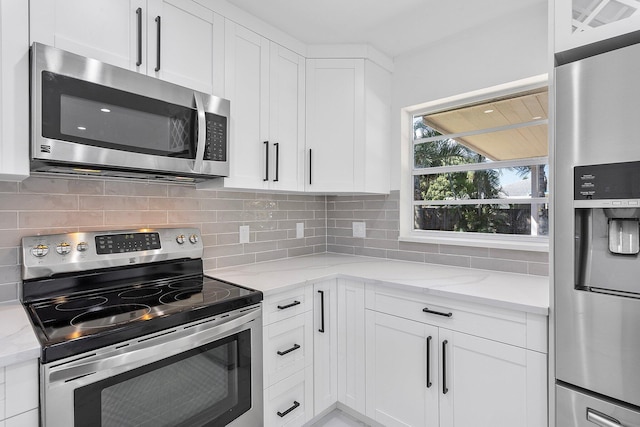 6887 Osborne Dr, Lake Worth, FL 33462 - kitchen featuring stainless steel appliances, white cabinetry, light stone countertops, and backsplash