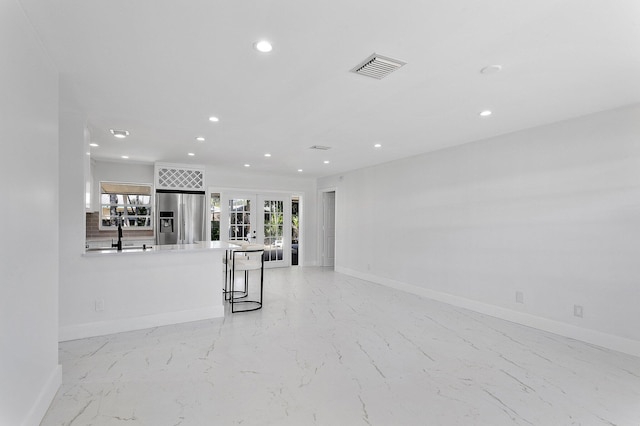 6887 Osborne Dr, Lake Worth, FL 33462 - unfurnished living room with light marble finish flooring, french doors, recessed lighting, baseboards, and a sink