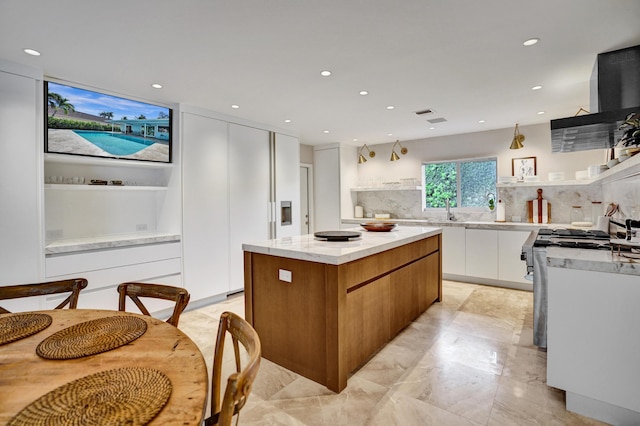 kitchen featuring modern cabinets, a kitchen island, white cabinetry, a sink, and gas range