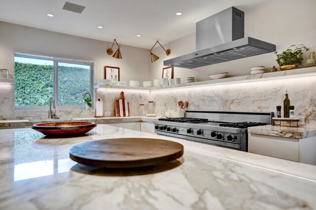 interior space featuring white cabinetry, wall chimney exhaust hood, tasteful backsplash, range, and recessed lighting
