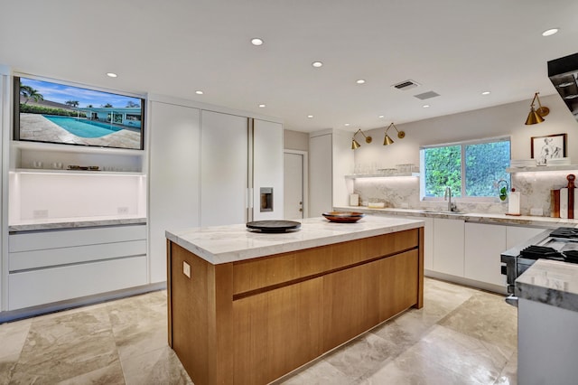 kitchen featuring a sink, modern cabinets, light stone counters, and visible vents