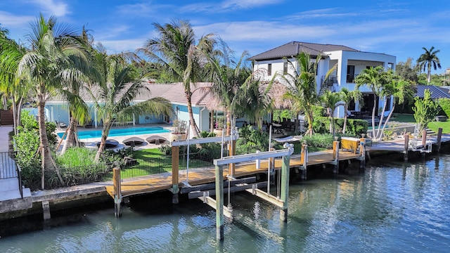 dock area with an outdoor pool, a patio, boat lift, a fenced backyard, and a water view