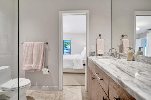 bathroom with baseboards, toilet, vanity, and ensuite bathroom