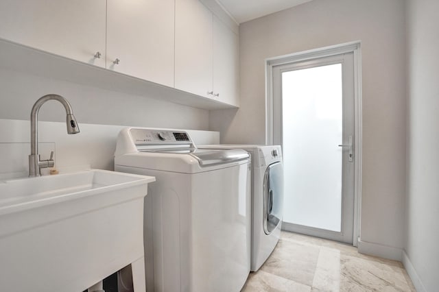 clothes washing area with baseboards, cabinet space, a sink, and separate washer and dryer