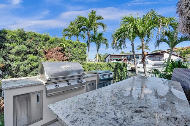 view of patio / terrace featuring an outdoor kitchen, outdoor dining area, a dock, and grilling area
