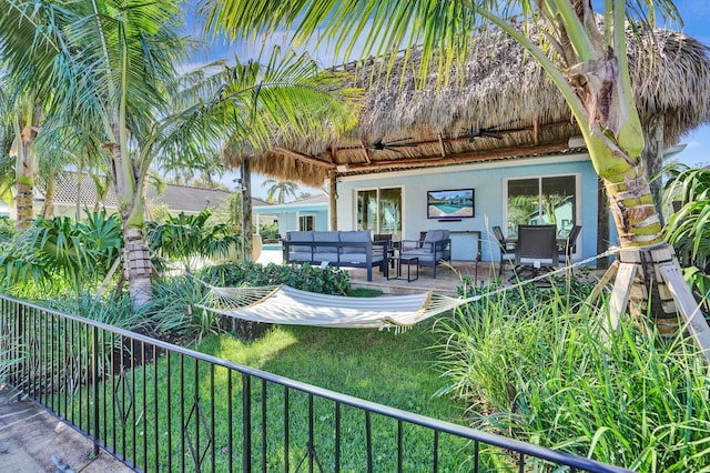 exterior space with an outdoor living space, fence, and a ceiling fan