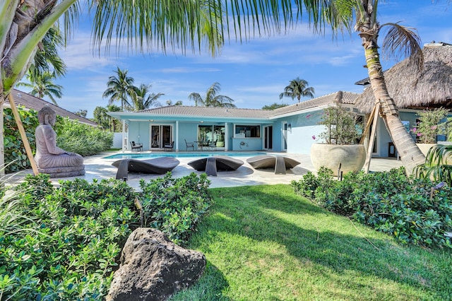 back of property with stucco siding, a tiled roof, a patio, a lawn, and an outdoor pool
