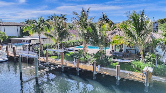 dock area with a water view, boat lift, a patio area, and an outdoor pool