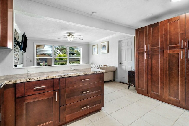 kitchen featuring open floor plan, light stone countertops, ceiling fan, and ornamental molding