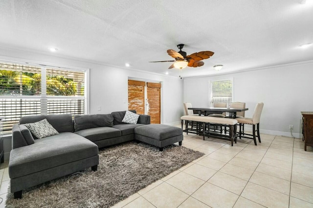 living area with light tile patterned floors, a textured ceiling, baseboards, and ceiling fan