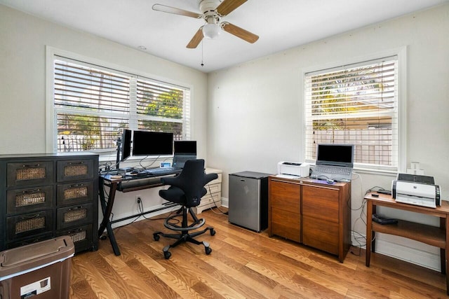 office space featuring light wood finished floors, baseboard heating, baseboards, and a ceiling fan
