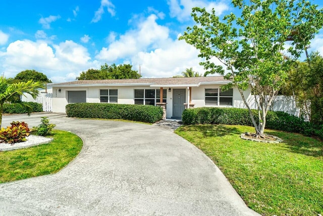 single story home with curved driveway, a front lawn, fence, stucco siding, and an attached garage