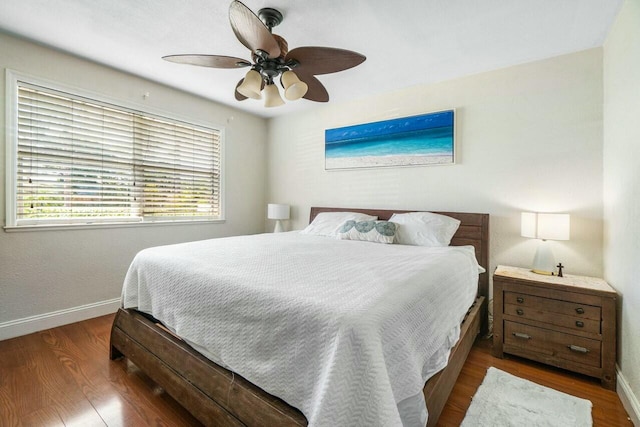 bedroom featuring baseboards, wood finished floors, and a ceiling fan
