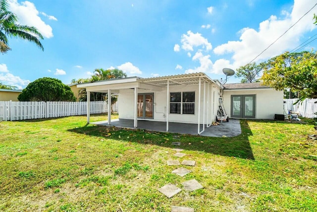 back of property featuring french doors, a patio, a yard, and a fenced backyard