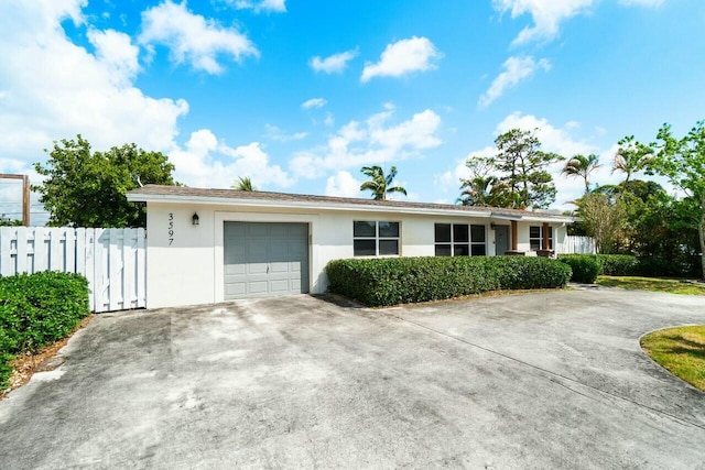single story home with concrete driveway, an attached garage, fence, and stucco siding