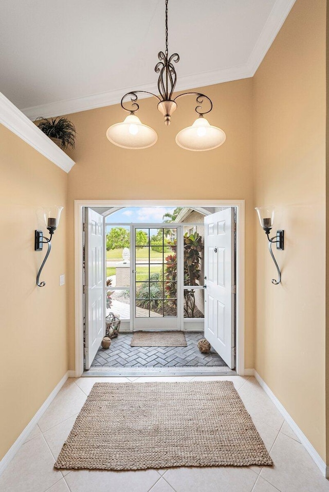 entrance foyer with ornamental molding, a chandelier, and light tile patterned floors