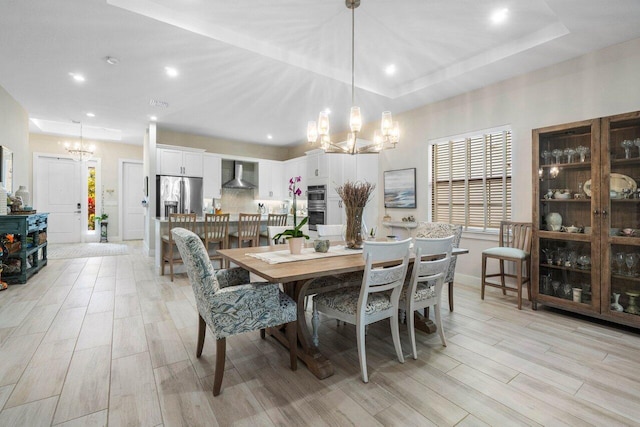dining room with a tray ceiling, light wood-style flooring, recessed lighting, and a chandelier