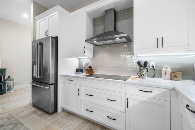 kitchen featuring backsplash, white cabinets, high end fridge, wall chimney exhaust hood, and black electric cooktop