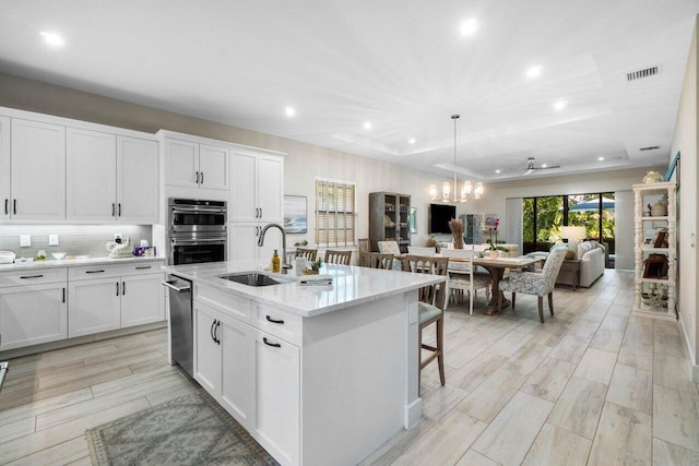 kitchen with a sink, stainless steel appliances, white cabinets, a kitchen breakfast bar, and open floor plan