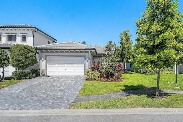 view of front of home featuring stucco siding, driveway, a garage, and a front lawn