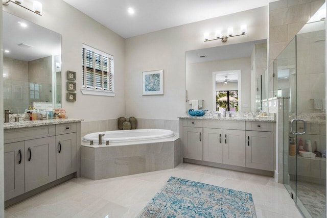 full bath featuring a sink, a garden tub, two vanities, and a shower stall