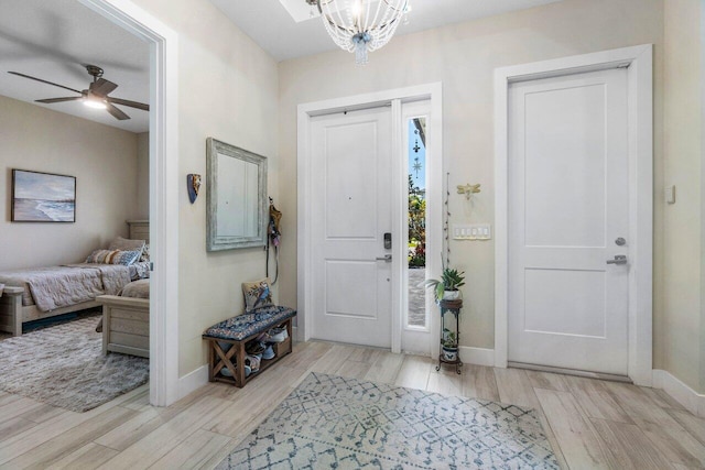 entryway featuring ceiling fan with notable chandelier, baseboards, and wood finish floors