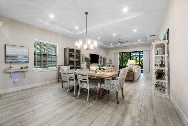 dining space featuring baseboards, a raised ceiling, and light wood-style floors