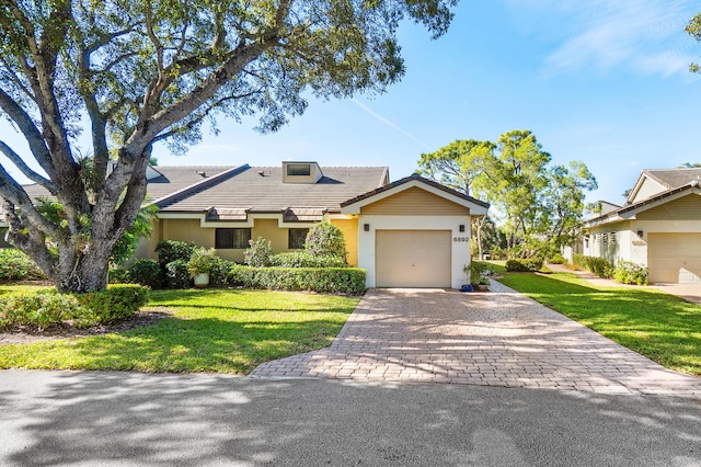 view of front of property featuring a tile roof, a front yard, stucco siding, an attached garage, and decorative driveway