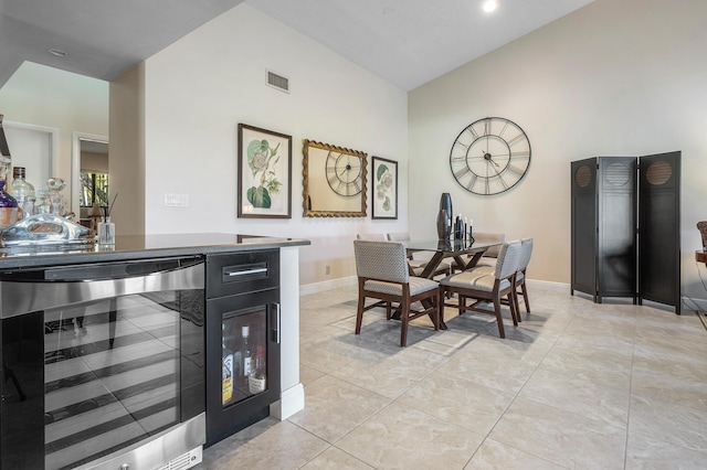 dining room featuring baseboards, visible vents, high vaulted ceiling, and wine cooler