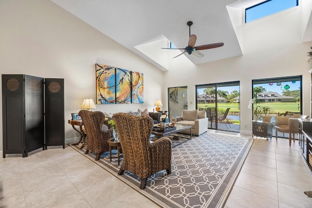 living room featuring light tile patterned flooring, a skylight, high vaulted ceiling, and a ceiling fan