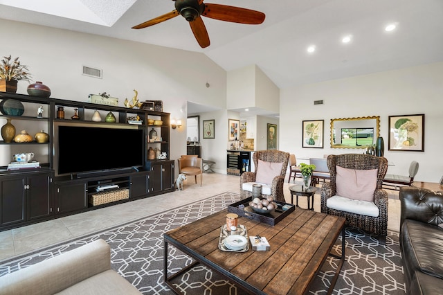 living room with high vaulted ceiling, a ceiling fan, a skylight, tile patterned flooring, and visible vents