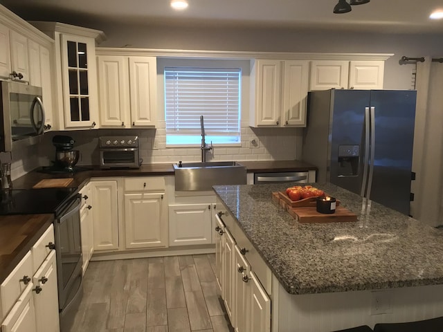 kitchen featuring fridge with ice dispenser, electric range, white cabinetry, dishwasher, and a sink