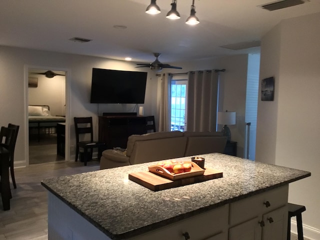 living area featuring light wood-type flooring, ceiling fan, baseboards, and visible vents