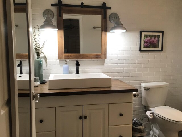 bathroom with toilet, vanity, and decorative backsplash