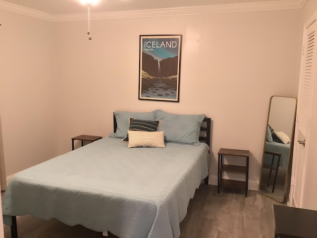 bedroom featuring crown molding, baseboards, and wood finished floors