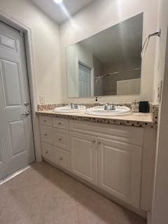 full bathroom with a shower, double vanity, tile patterned flooring, and a sink