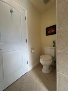 bathroom with toilet, tile patterned floors, and baseboards